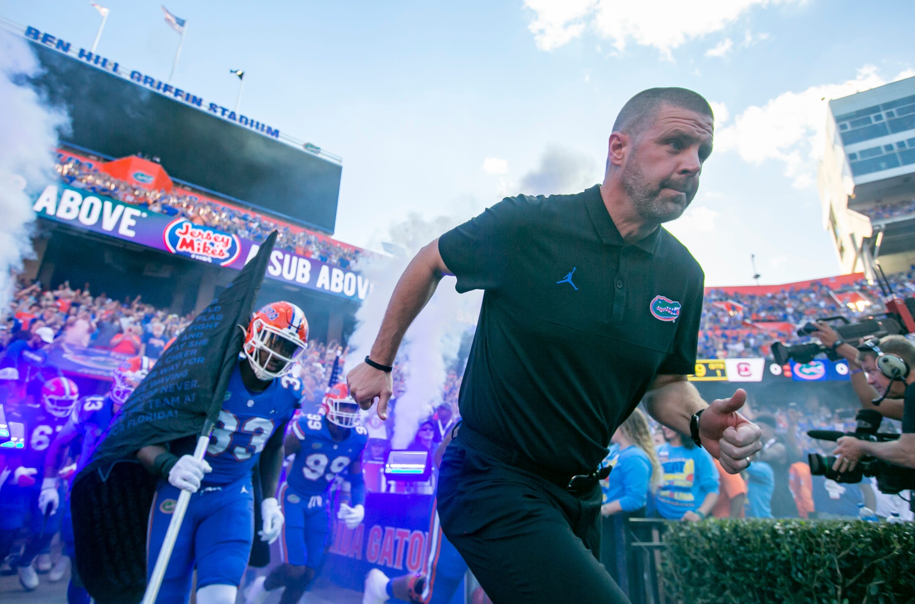 Florida Gators head coach Billy Napier leads his team out onto the field.