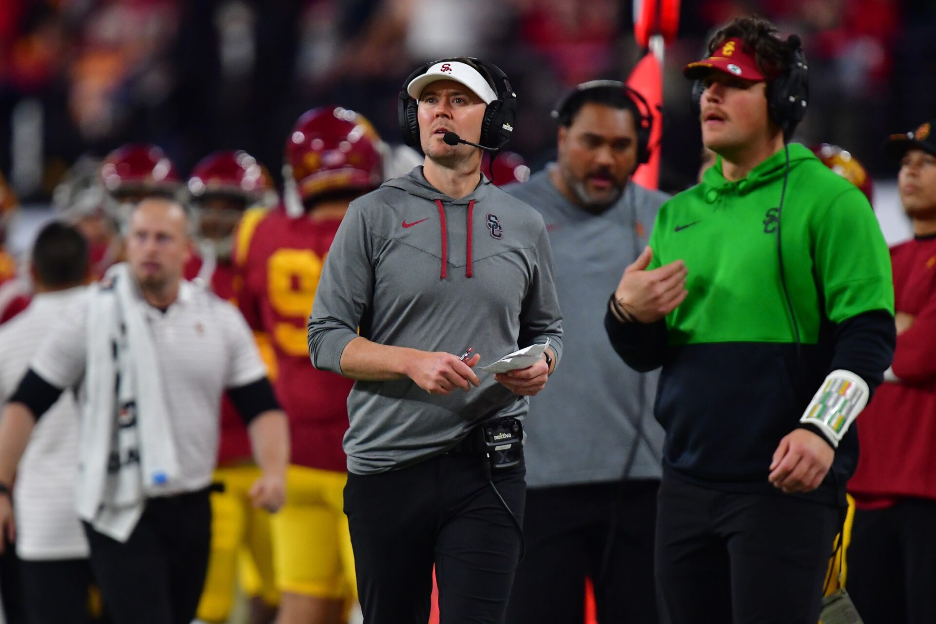 USC Trojans head coach Lincoln Riley watches the game from the sidelines along with other coaches and players.
