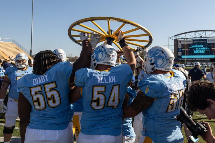 The Kent State Golden Flashes hoist the Wagon Wheel after defeating the University of Akron.