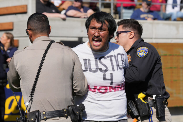 Protestors took to the field to delay the kickoff of the USC-Cal game in protest of the suspended Ivonne del Valle, a UC Berkeley professor.