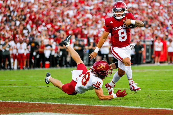 Oklahoma's Dillon Gabriel (8) runs the ball and jumps over Iowa State's Ben Nikkel (18) to score a touchdown in the first quarter during an NCAA football game between University of Oklahoma (OU) and Iowa State at the Gaylord Family Oklahoma Memorial Stadium in Norman, Okla., on Saturday, Sept. 30, 2023.