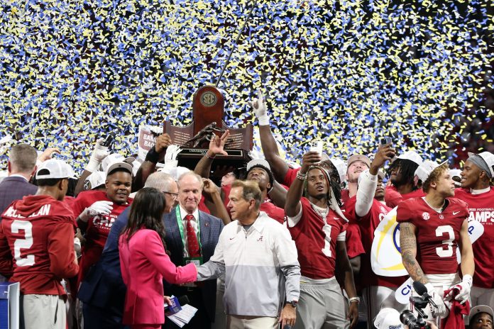 Alabama Crimson Tide head coach Nick Saban and players celebrate with the trophy on the podium after defeating the Georgia Bulldogs in the SEC championship game at Mercedes-Benz Stadium.
