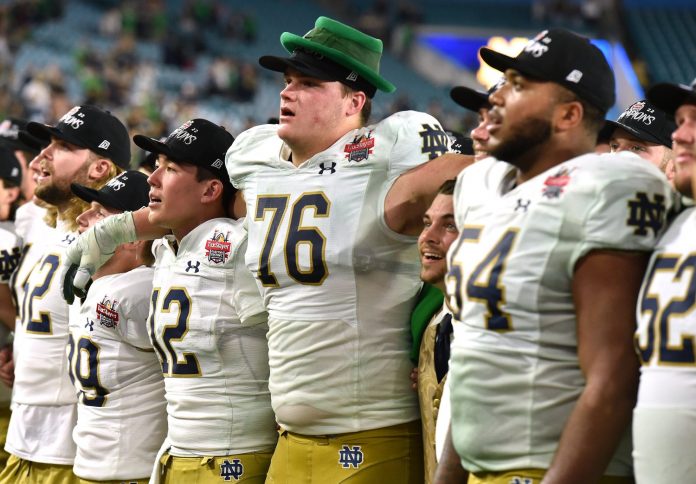 Notre Dame Fighting Irish quarterback Tyler Buchner (12) with teammate offensive lineman Joe Alt (76) and the team leprechaun mascot Ryan Coury sing the School's Alma mater after their victory over South Carolina in the Gator Bowl.