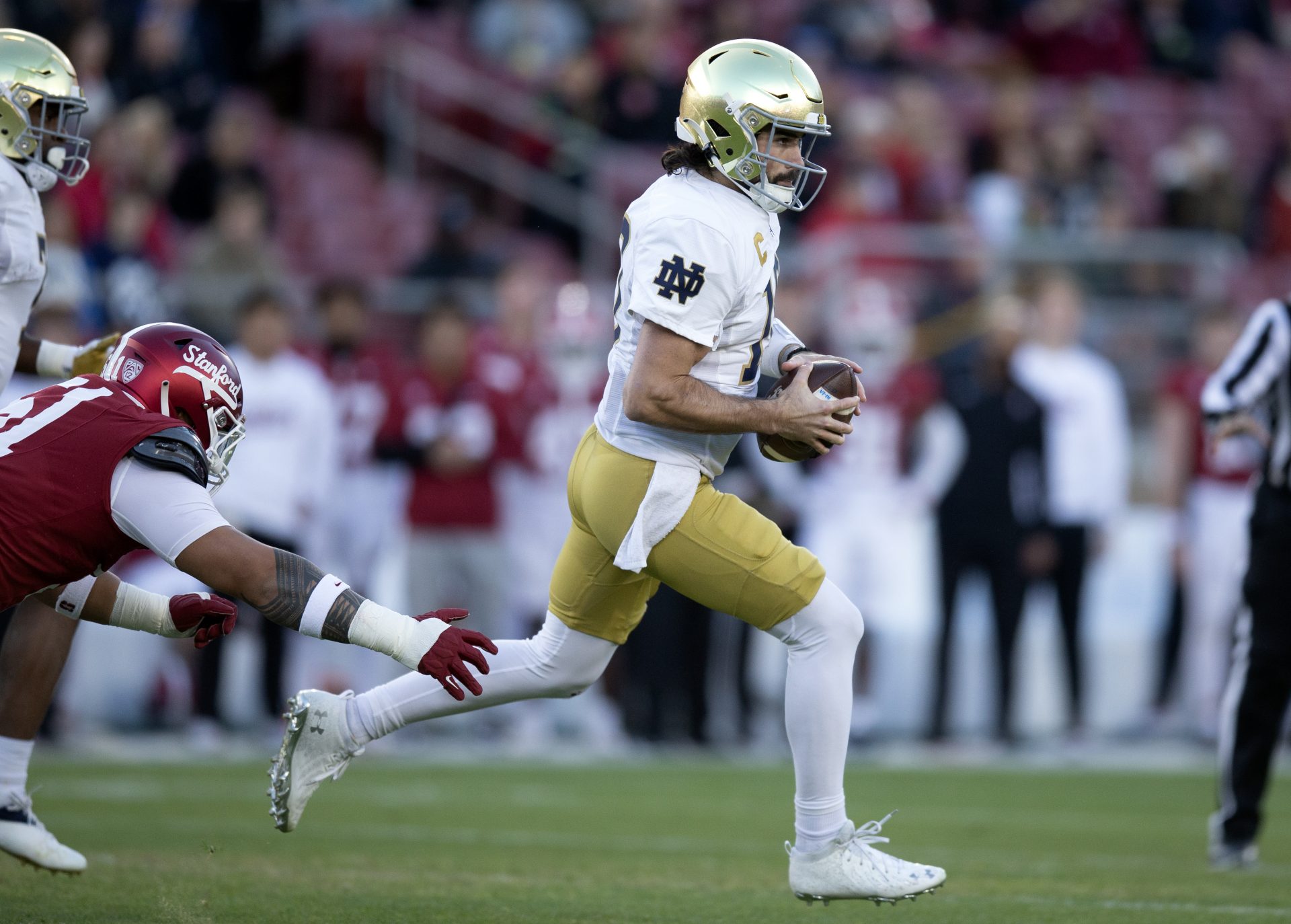 Notre Dame Fighting Irish quarterback Sam Hartman (10) scrambles away from pressure by Stanford Cardinal defensive lineman Jaxson Moi (51) during the first quarter at Stanford Stadium