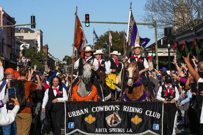 The Urban Cowboys Riding Club carries Texas Longhorns and Washington Huskies flags in the Sugar Bowl New Year's Eve Parade on Sunday, Dec. 31, 2023 in New Orleans, Louisiana.