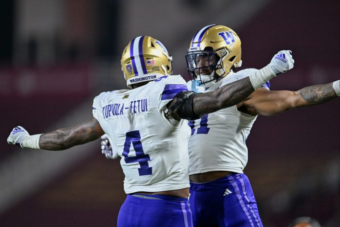 Washington Huskies defensive end Zion Tupuola-Fetui (4) celebrates with Washington Huskies defensive end Lance Holtzclaw (41) after recovering a fumbled ball from the USC Trojans during the second quarter at United Airlines Field at Los Angeles Memorial Coliseum.
