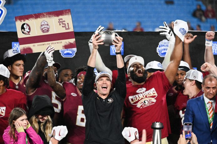 Dec 2, 2023; Charlotte, NC, USA; Florida State Seminoles head coach Mike Norvell raises the ACC Championship trophy with his players after the game against the Louisville Cardinals at Bank of America Stadium. Mandatory Credit: Bob Donnan-USA TODAY Sports