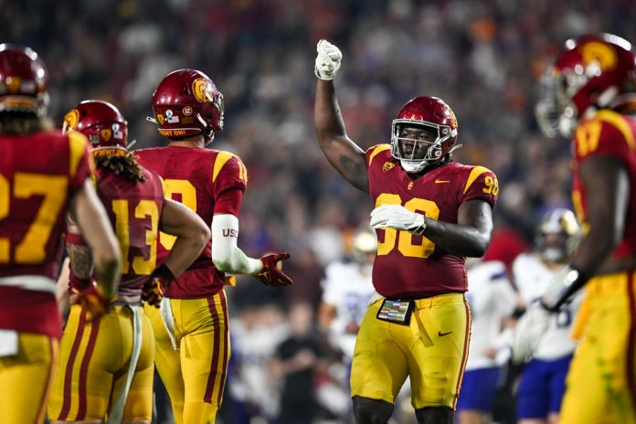 USC Trojans defensive lineman Bear Alexander (90) celebrates with linebacker Eric Gentry (18) and other teammates against the Washington Huskies during the fourth quarter at United Airlines Field at Los Angeles Memorial Coliseum.