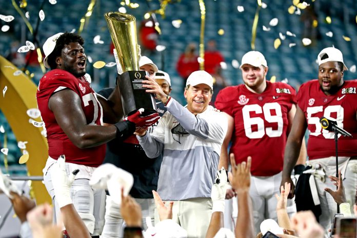 Alabama Crimson Tide head coach Nick Saban and offensive lineman Alex Leatherwood (70) celebrates with the CFP National Championship trophy after beating the Ohio State Buckeyes in the 2021 College Football Playoff National Championship Game.