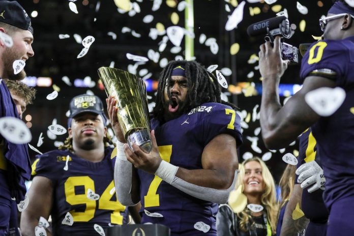Michigan running back Donovan Edwards picks up the trophy to celebrate 34-13 win over Washington at the national championship game at NRG Stadium in Houston.