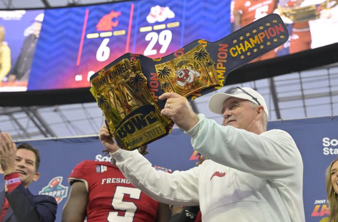 Fresno State Bulldogs head coach Jeff Tedford is awarded the championship belt from Jimmy Kimmel after defeating the Washington State Cougars in the LA Bowl at SoFi Stadium.