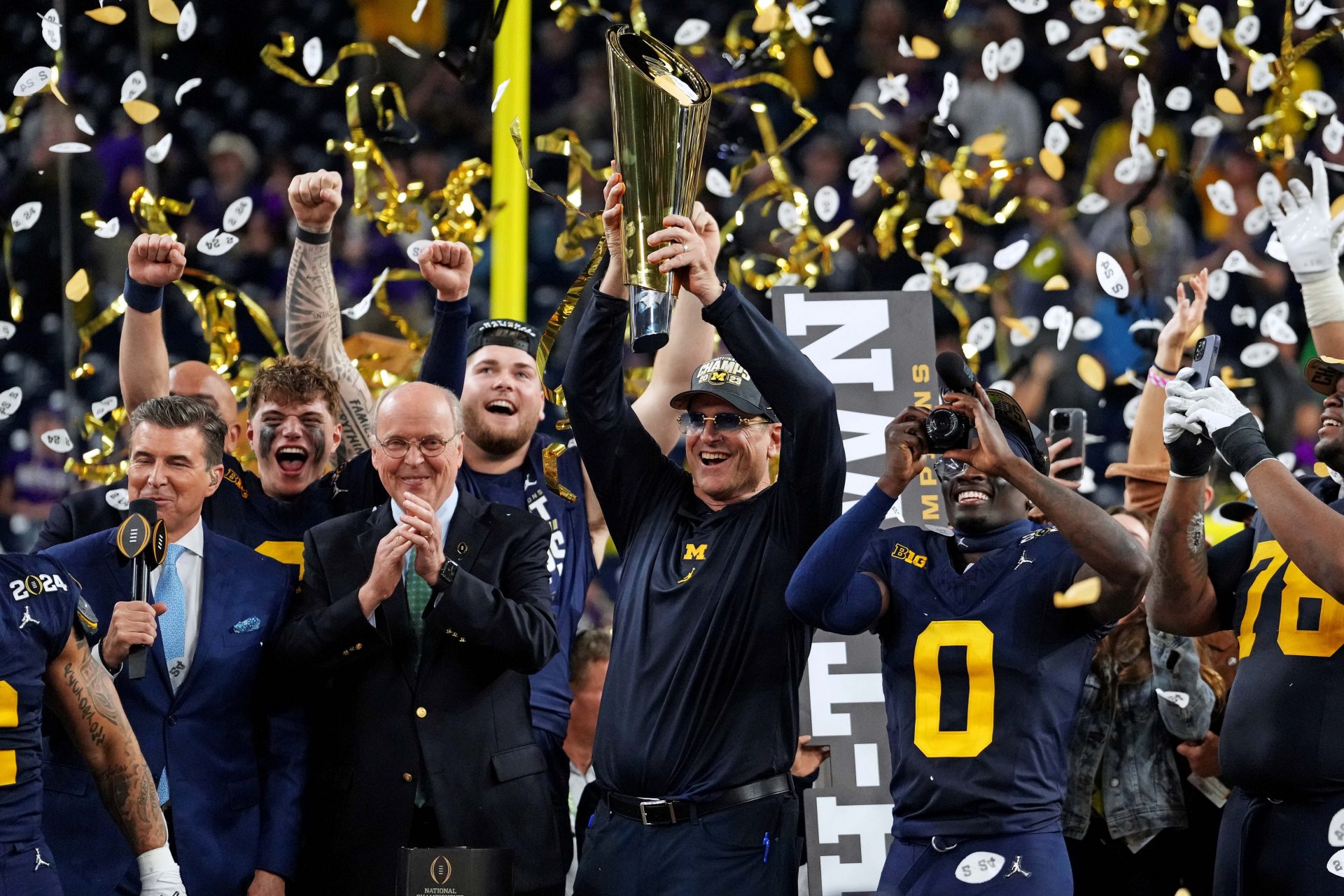 Michigan Wolverines head coach Jim Harbaugh celebrates with the CFP Championship trophy after beating the Washington Huskies in the 2024 College Football Playoff national championship game at NRG Stadium.