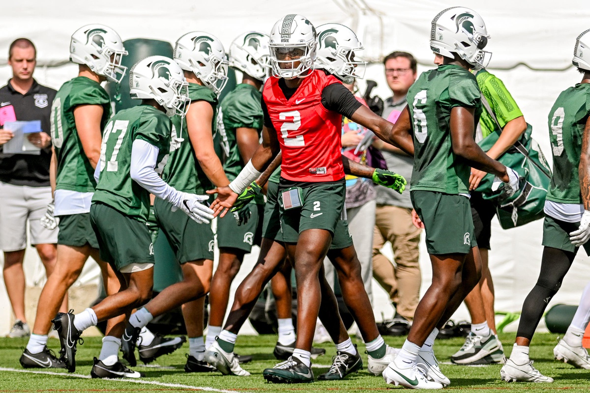 Michigan State Spartans quarterback Aidan Chiles, center, slaps hands with teammates during the first day of football camp on Tuesday, July 30, 2024, in East Lansing.