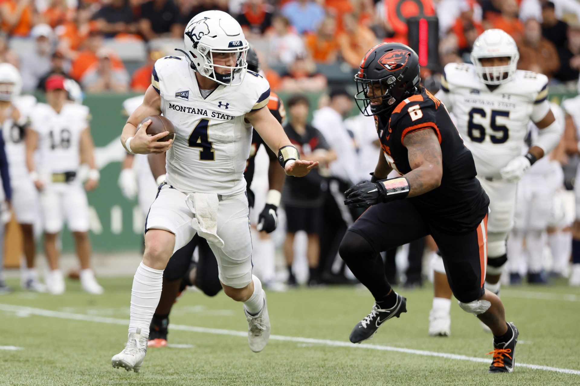 Montana State Bobcats quarterback Tommy Mellott (4) scrambles under pressure from Oregon State Beavers linebacker John McCartan (6) during the first half at Providence Park.