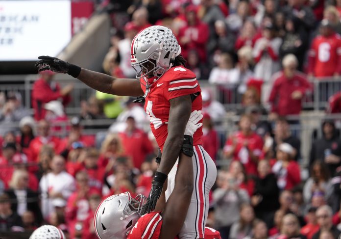 Ohio State Buckeyes wide receiver Jeremiah Smith (4) is hoisted in the air by Ohio State Buckeyes offensive lineman Tegra Tshabola (77) after scoring a touchdown during the first half at Ohio Stadium.