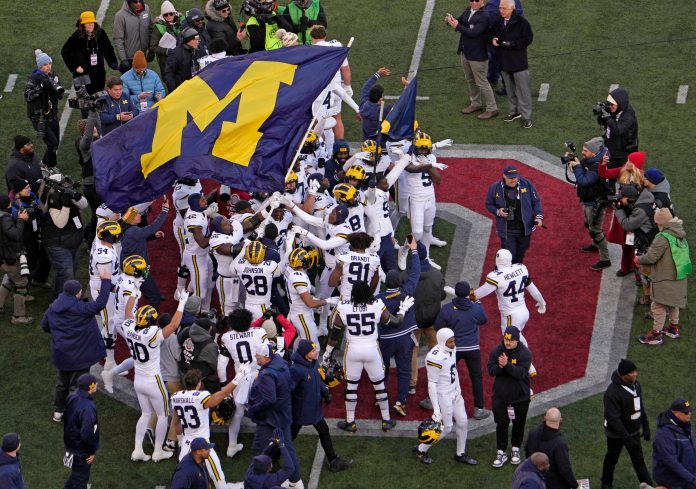 Michigan football players plant their team’s flag at midfield following Saturday’s NCAA Division I football game against the Ohio State Buckeyes at Ohio Stadium. The Michigan Wolverines won the game 13-10.