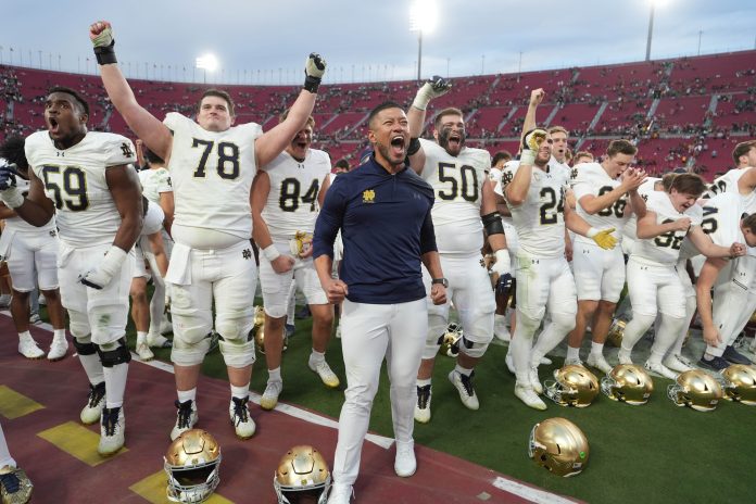 Notre Dame Fighting Irish head coach Marcus Freeman celebrates with players at the end of the game against the Southern California Trojans at United Airlines Field at Los Angeles Memorial Coliseum.