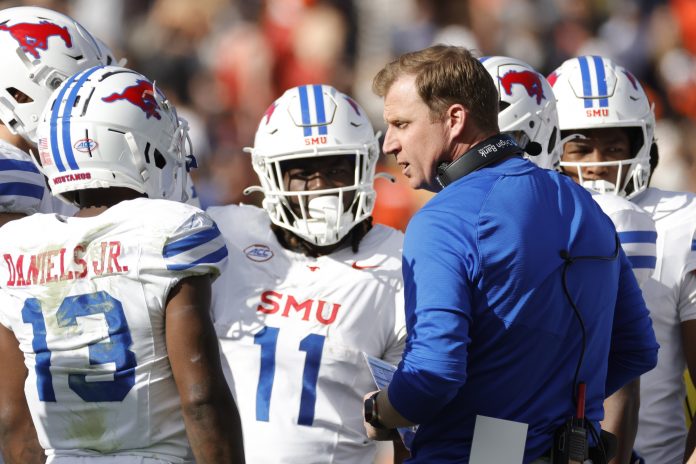 Southern Methodist Mustangs head coach Rhett Lashlee (center) huddles with players during a stoppage in play in the first half against the Virginia Cavaliers at Scott Stadium.