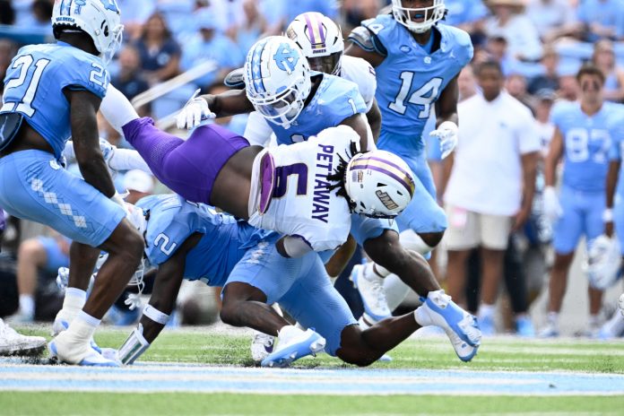 James Madison Dukes running back George Pettaway (6) is tackled by North Carolina Tar Heels defensive backs Kaleb Cost (21) and Jakeen Harris (2) and Antavious Lane (1) in the second quarter at Kenan Memorial Stadium.