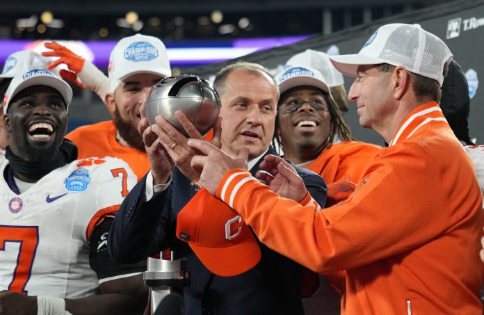 ACC commissioner James Phillips presents Clemson Tigers head coach Dabo Swinney with the trophy after the Tigers won the 2024 ACC Championship game against the Southern Methodist Mustangs at Bank of America Stadium.