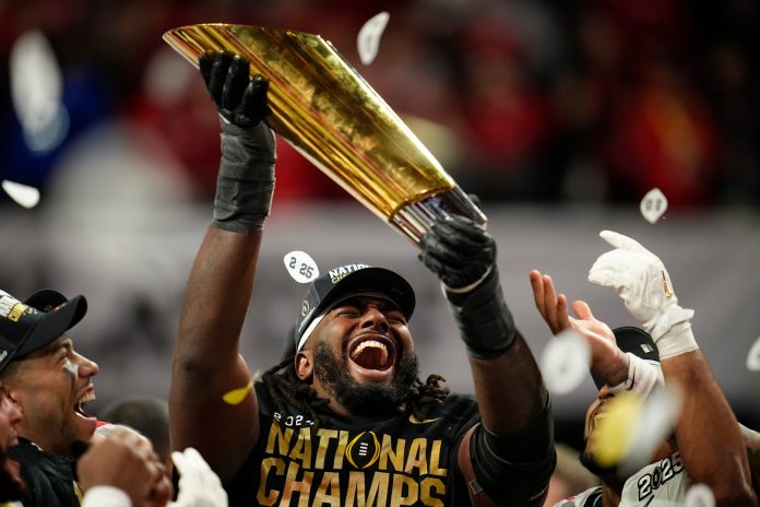 Ohio State Buckeyes offensive lineman Donovan Jackson (74) holds the trophy following the 34-23 win over the Notre Dame Fighting Irish to win the College Football Playoff National Championship at Mercedes-Benz Stadium in Atlanta on Jan. 21, 2025.