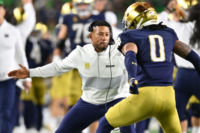 Notre Dame Fighting Irish head coach Marcus Freeman celebrates with safety Xavier Watts (0) after Watts intercepted a pass in the first quarter against the USC Trojans at Notre Dame Stadium.