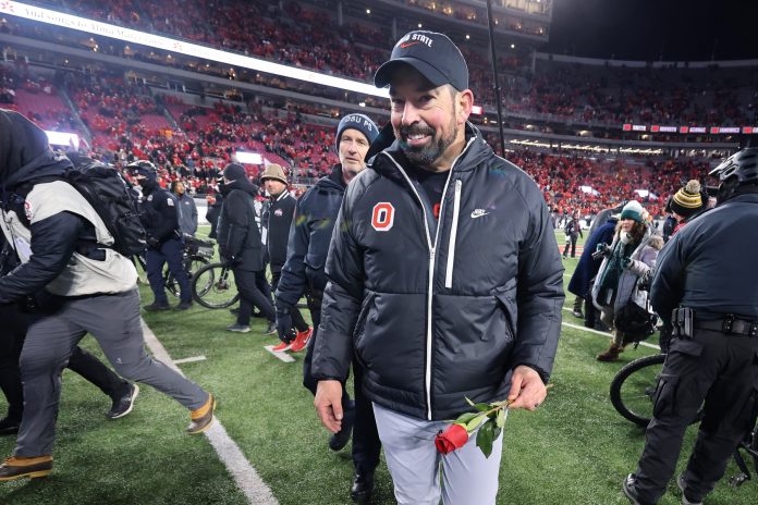 Ohio State Buckeyes head coach Ryan Day celebrates the win as he carries a rose after the game against the Tennessee Volunteers at Ohio Stadium.