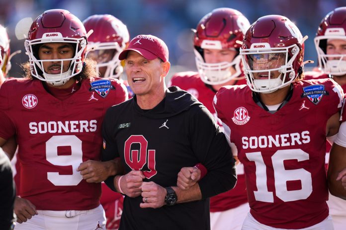 Oklahoma coach Brent Venables locks arms with players before the Armed Forces Bowl football game between the University of Oklahoma Sooners (OU) and the Navy Midshipmen at Amon G. Carter Stadium in Fort Worth, Texas.