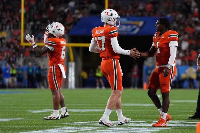 Miami Hurricanes quarterback Emory Williams (17) shakes hands with quarterback Cam Ward (1) after a touchdown against the Iowa State Cyclones during the second half at Camping World Stadium.