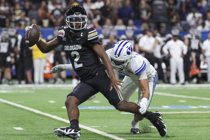 Colorado Buffaloes quarterback Shedeur Sanders (2) attempts to avoid a tackle by Brigham Young Cougars safety Raider Damuni (3) during the second quarter at Alamodome.