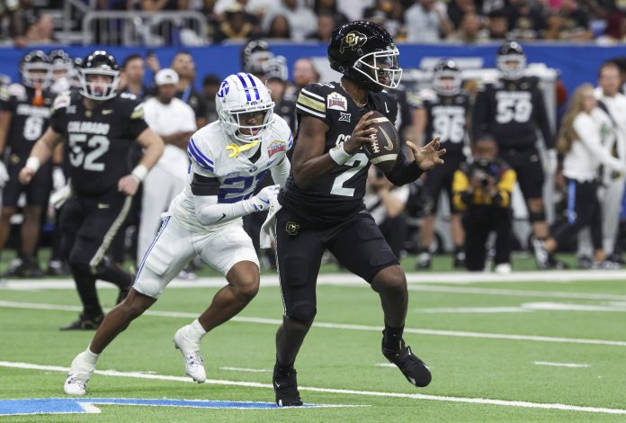 Colorado Buffaloes quarterback Shedeur Sanders (2) runs with the ball as Brigham Young Cougars cornerback Evan Johnson (21) attempts to make a tackle during the third quarter at Alamodome.