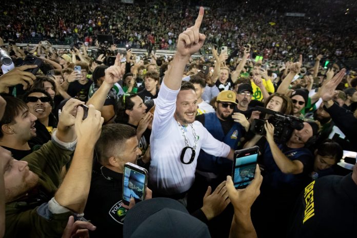 Coach Dan Lanning celebrates amid a crowd of fans on the field as No. 3 Oregon knocked off No. 2 Ohio State 32-31.