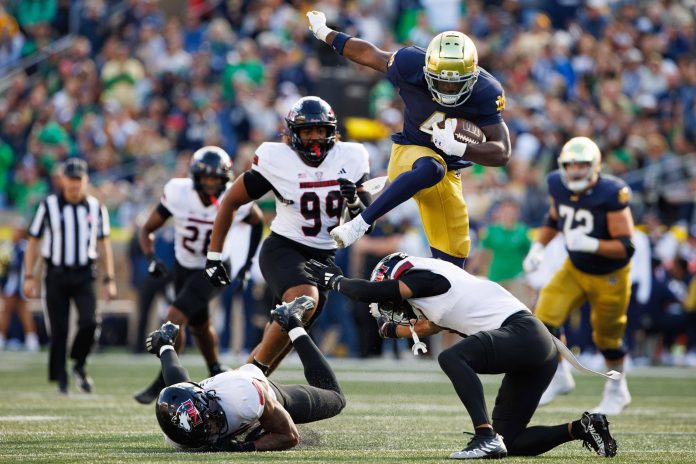 Notre Dame running back Jeremiyah Love (4) hurdles over Northern Illinois safety Nate Valcarcel on his way to score a touchdown during a NCAA college football game at Notre Dame Stadium on Saturday, Sept. 7, 2024, in South Bend.