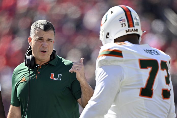 Miami Hurricanes head coach Mario Cristobal talks with offensive lineman Anez Cooper (73) during the first half against the Louisville Cardinals at L&N Federal Credit Union Stadium.