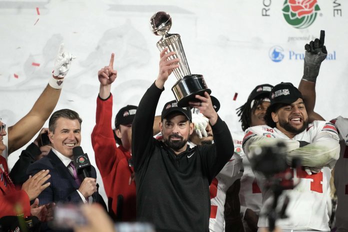 Ohio State Buckeyes head coach Ryan Day holds the Leishman Trophy after a CFP Quarterfinal against the Oregon Ducks at Rose Bowl Stadium.