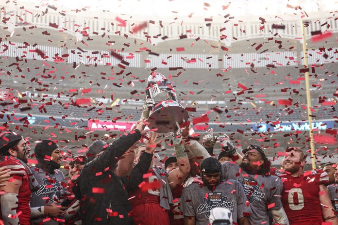 Nebraska Cornhuskers head coach Matt Rhule holds the championship trophy as Cornhuskers players celebrate after the game against the Boston College Eagles at Yankee Stadium.