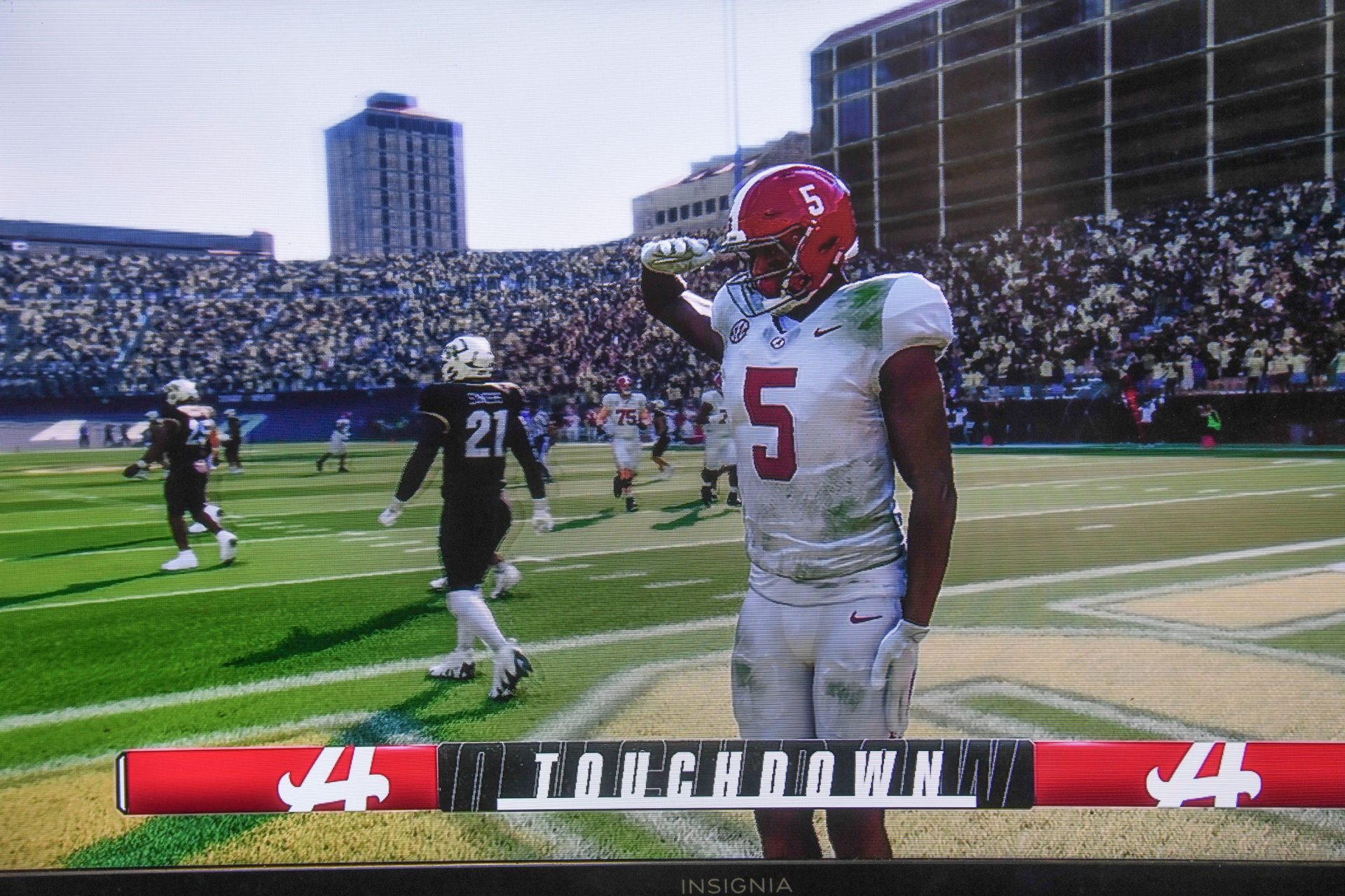 An Alabama player salutes a touchdown as two people play the new EA Sports College Football 25 video game at the McDonald Hughes Center in Tuscaloosa.