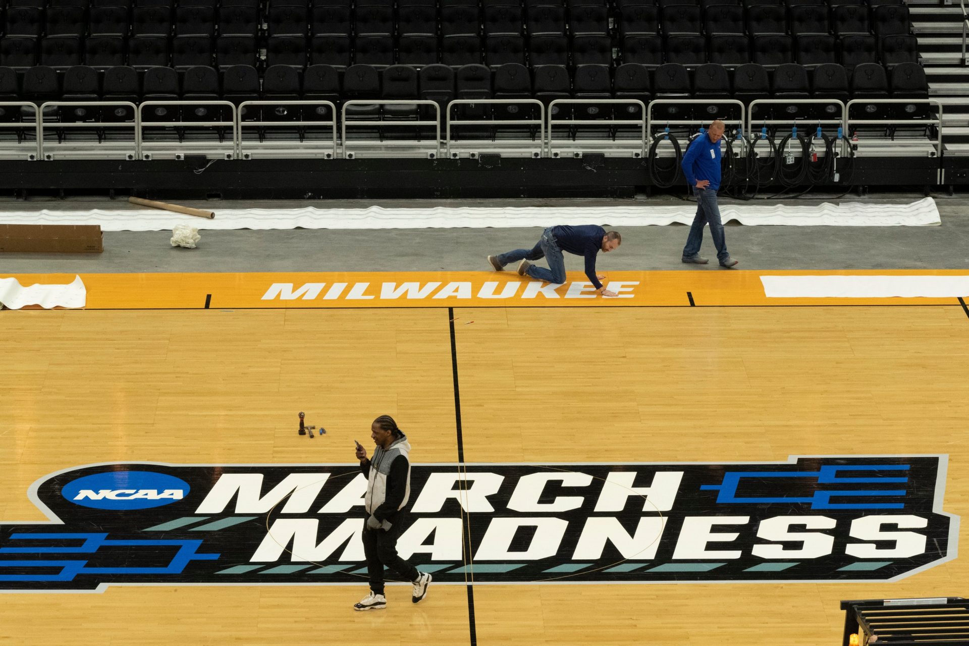 Workers install the court for the NCAA men's basketball regional games at Fiserv Forum Monday, March 14, 2022 in Milwaukee, Wis.