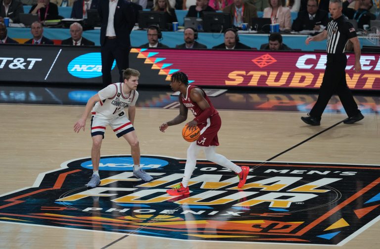 Alabama Crimson Tide guard Latrell Wrightsell Jr. (12) dribbles the ball up the court against Connecticut Huskies guard Cam Spencer (12) in the semifinals of the men's Final Four of the 2024 NCAA Tournament at State Farm Stadium.