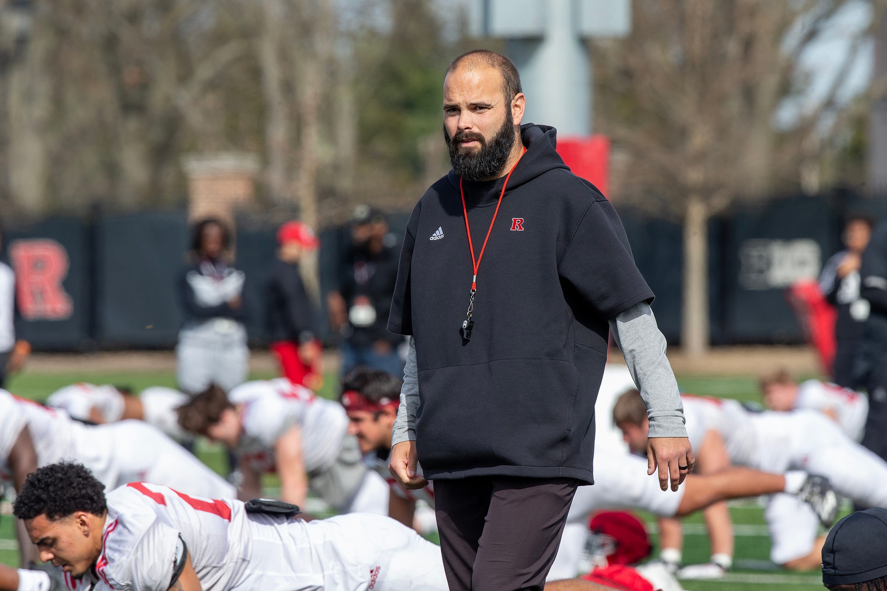 Defensive coordinator Joe Harasymiak observes warm up exercises before Rutgers University football spring practice