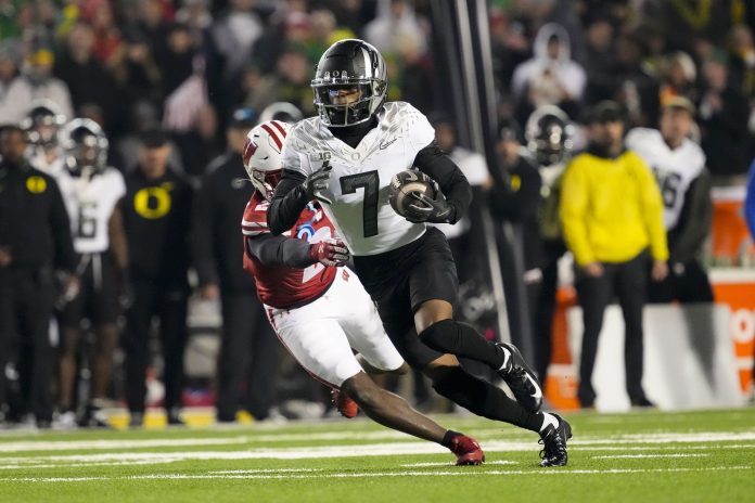 Oregon Ducks wide receiver Evan Stewart (7) rushes with the football in front of Wisconsin Badgers cornerback Ricardo Hallman (2) after catching a pass during the fourth quarter at Camp Randall Stadium.