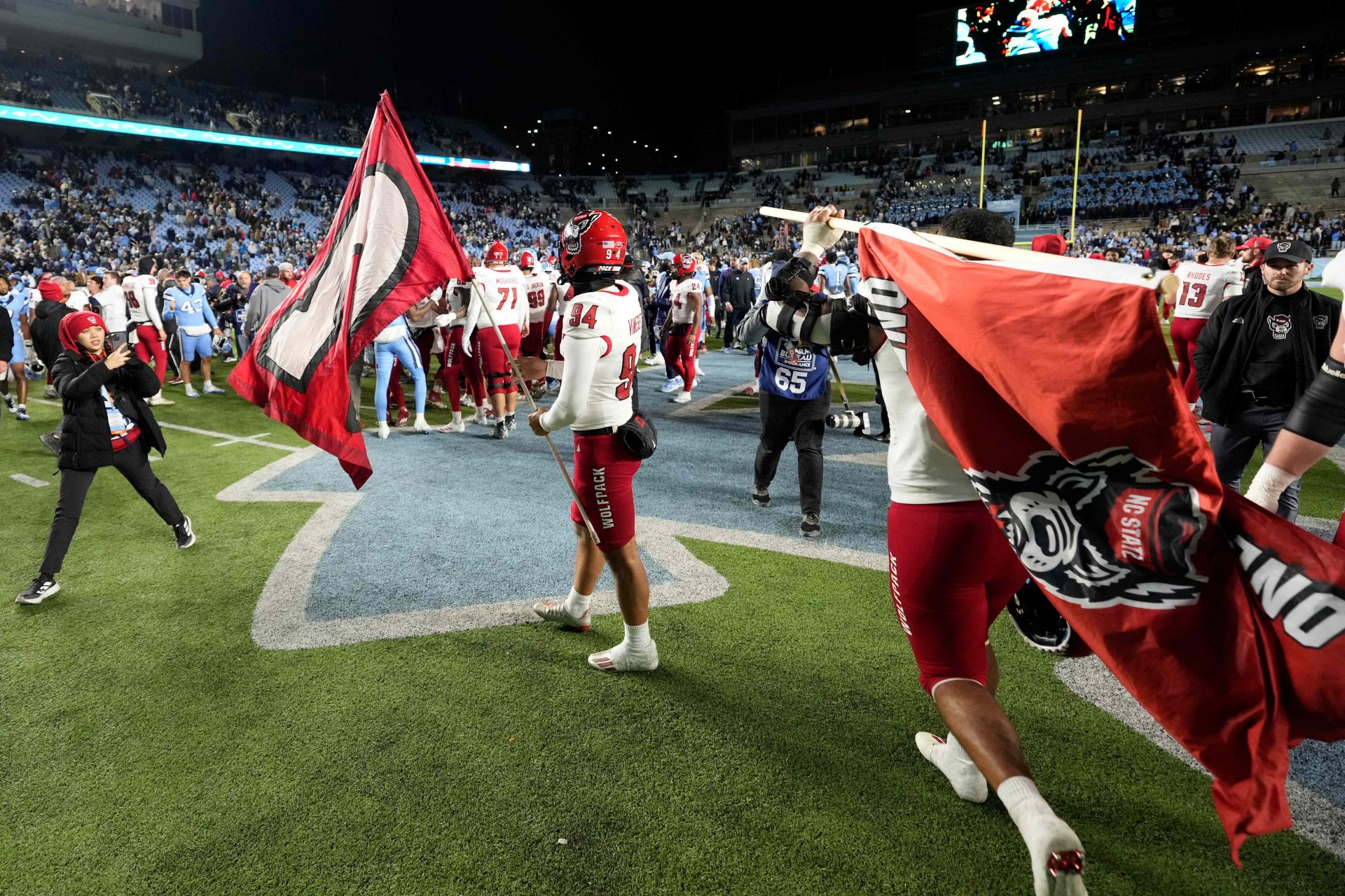 North Carolina State Wolfpack players carry Wolfpack flags toward midfield after the game at Kenan Memorial Stadium.