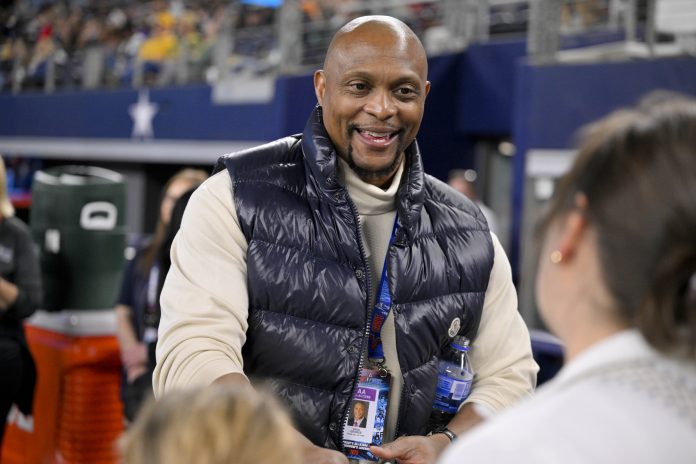 Former NFL player Eddie George signs a football for the fans during the second half of the game between the East and the West