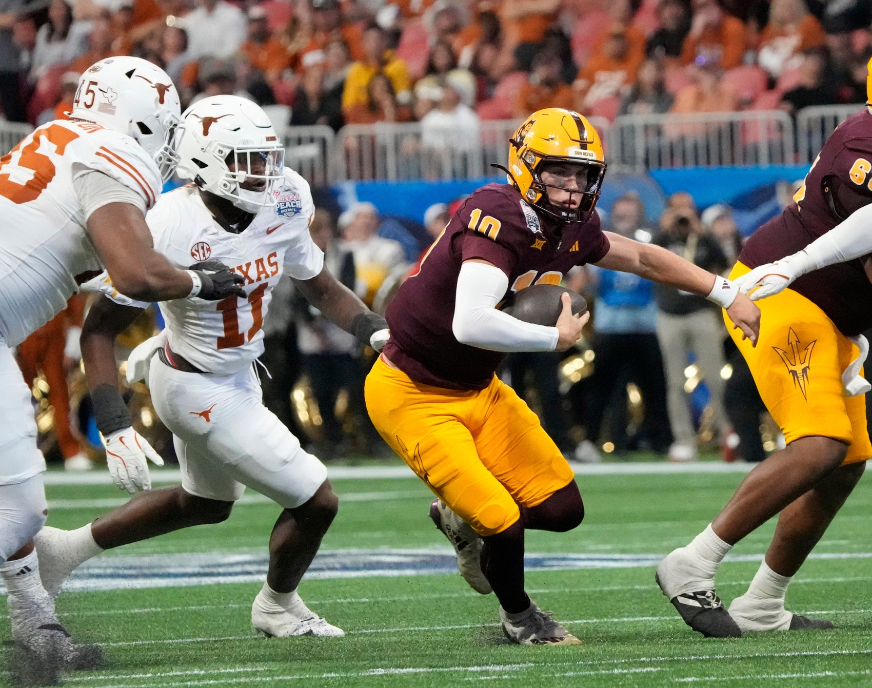 Arizona State quarterback Sam Leavitt (10) scrambles away from Texas linebacker Colin Simmons (11) during the second quarter of the Chick-fil-A Peach Bowl in Atlanta on Wednesday, Jan. 1, 2025.