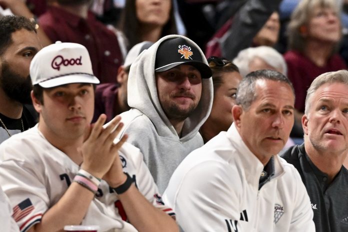 Former NLF quarterback Johnny Manziel, center, sits court side during the game between the Texas A&M Aggies and the Auburn Tigers at Reed Arena.