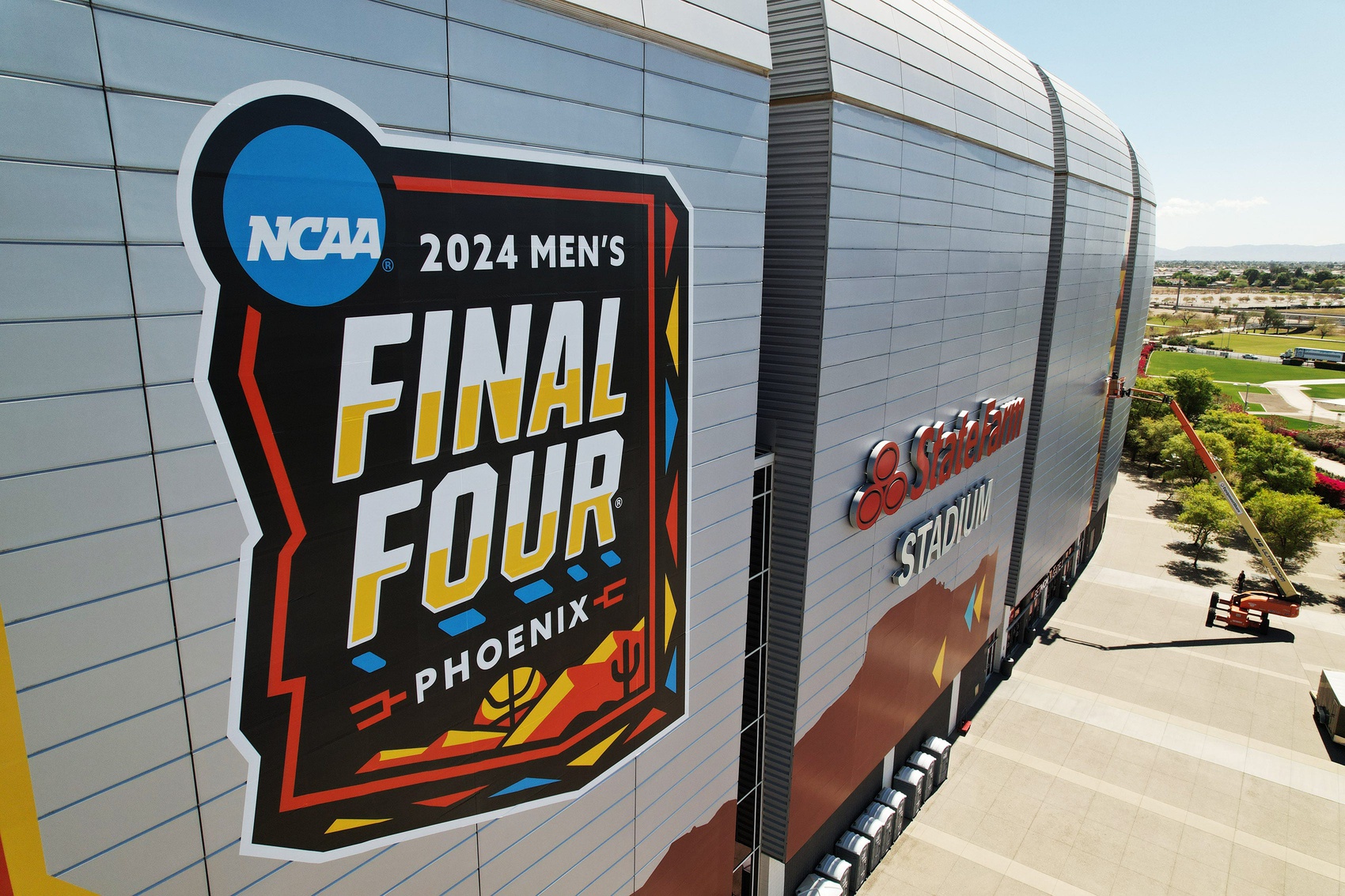 Workers install logos on the exterior of State Farm Stadium in preparations for the Final Four April 6-8.