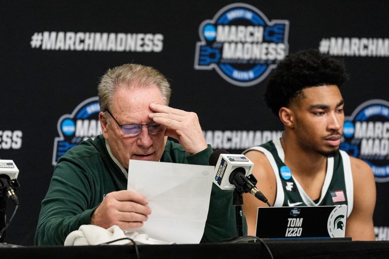 Michigan State head coach Tom Izzo, left, reads stats of the game as guard Jaden Akins (3) answers questions at post game press conference