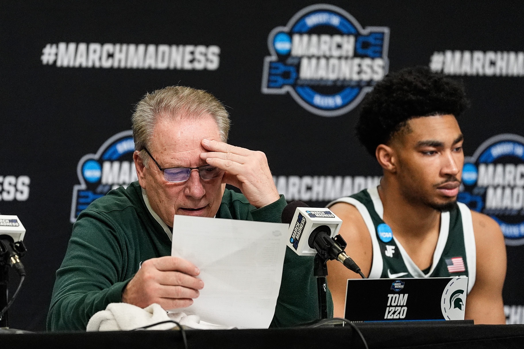 Michigan State head coach Tom Izzo, left, reads stats of the game as guard Jaden Akins (3) answers questions at post game press conference