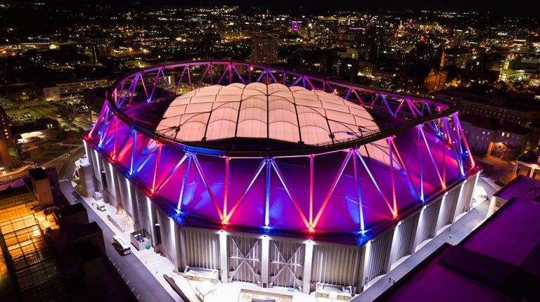 An aerial shot of the Syracuse University Stadium lit up at night.