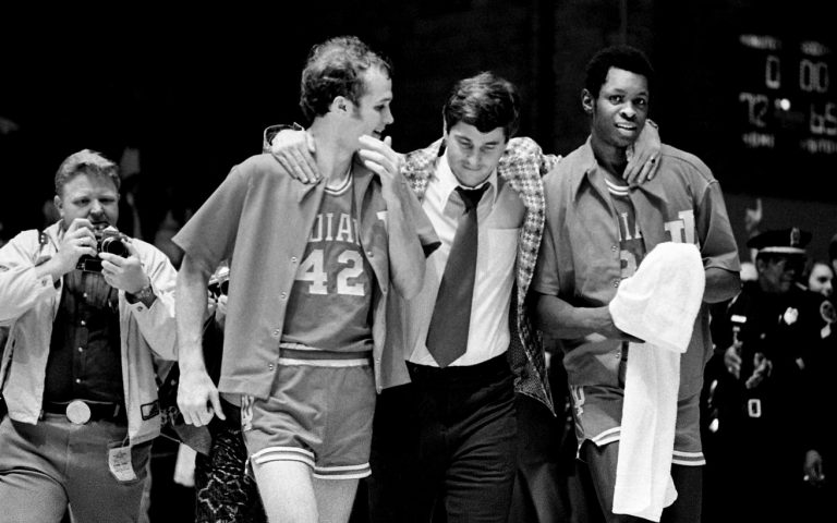Indiana coach Bobby Knight, center, walks with seniors John Ritter (42) and Steve Downing, right, to accept the trophy after they defeated Kentucky 72-65 to win the Mideast Regional championship